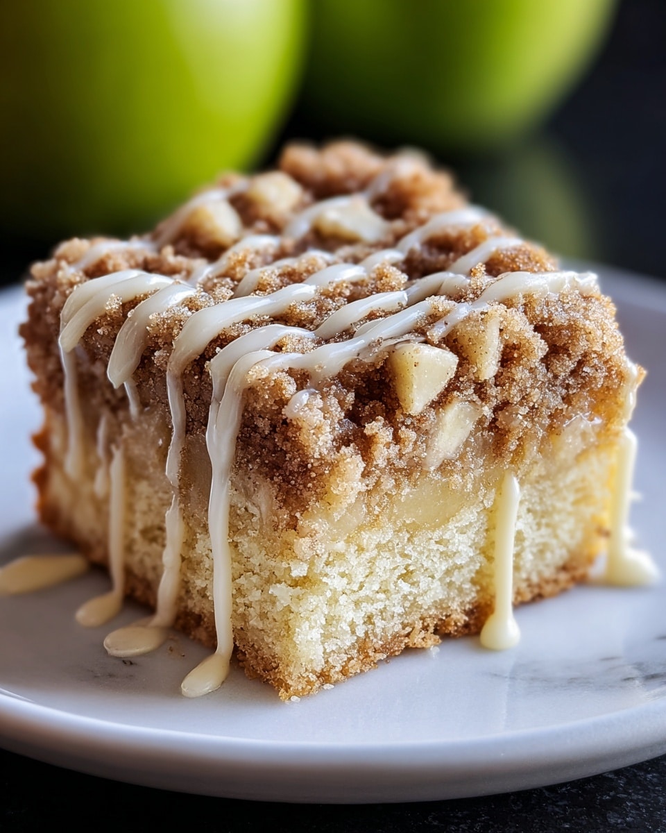 A piece of crumb cake with two layers: the bottom layer is light yellow and soft with a crumbly texture, while the top layer is a thick brown crumb topping mixed with small light-colored chunks. The whole cake is drizzled with light cream-colored icing in thin lines flowing down the sides. It sits on a plain white plate with a white marbled surface in the background and a blurred green apple behind the cake. Photo taken with an iphone --ar 4:5 --v 7