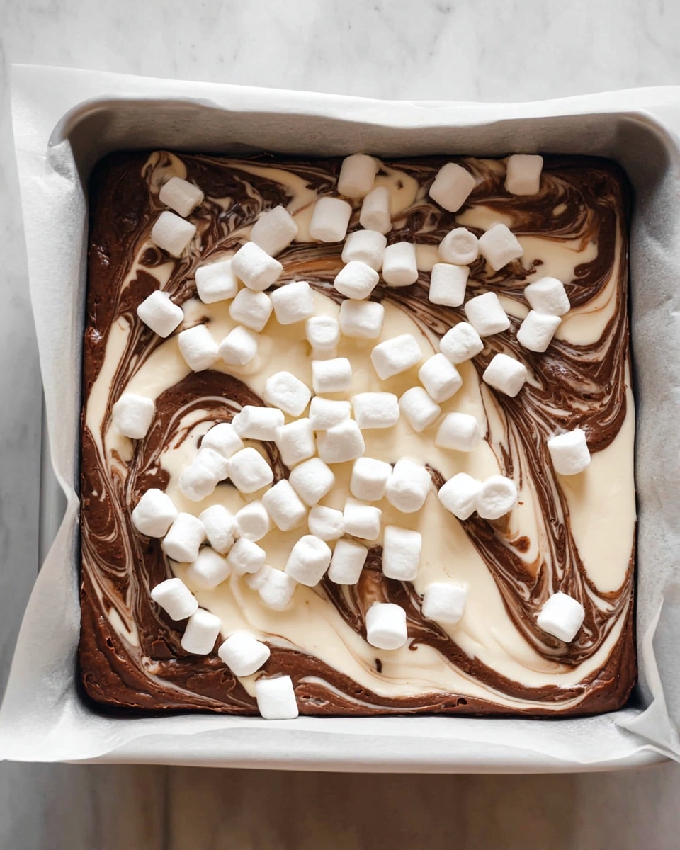 The image shows one layer of swirl brownie batter in a white baking pan lined with parchment paper. The batter has two colors, dark brown and creamy white, mixed together in a marbled pattern that covers the whole pan. On top of the batter, there is a layer of small white marshmallows spread evenly across the surface with some marshmallows gathered near the edges. The pan sits on a white marbled surface. Photo taken with an iphone --ar 4:5 --v 7