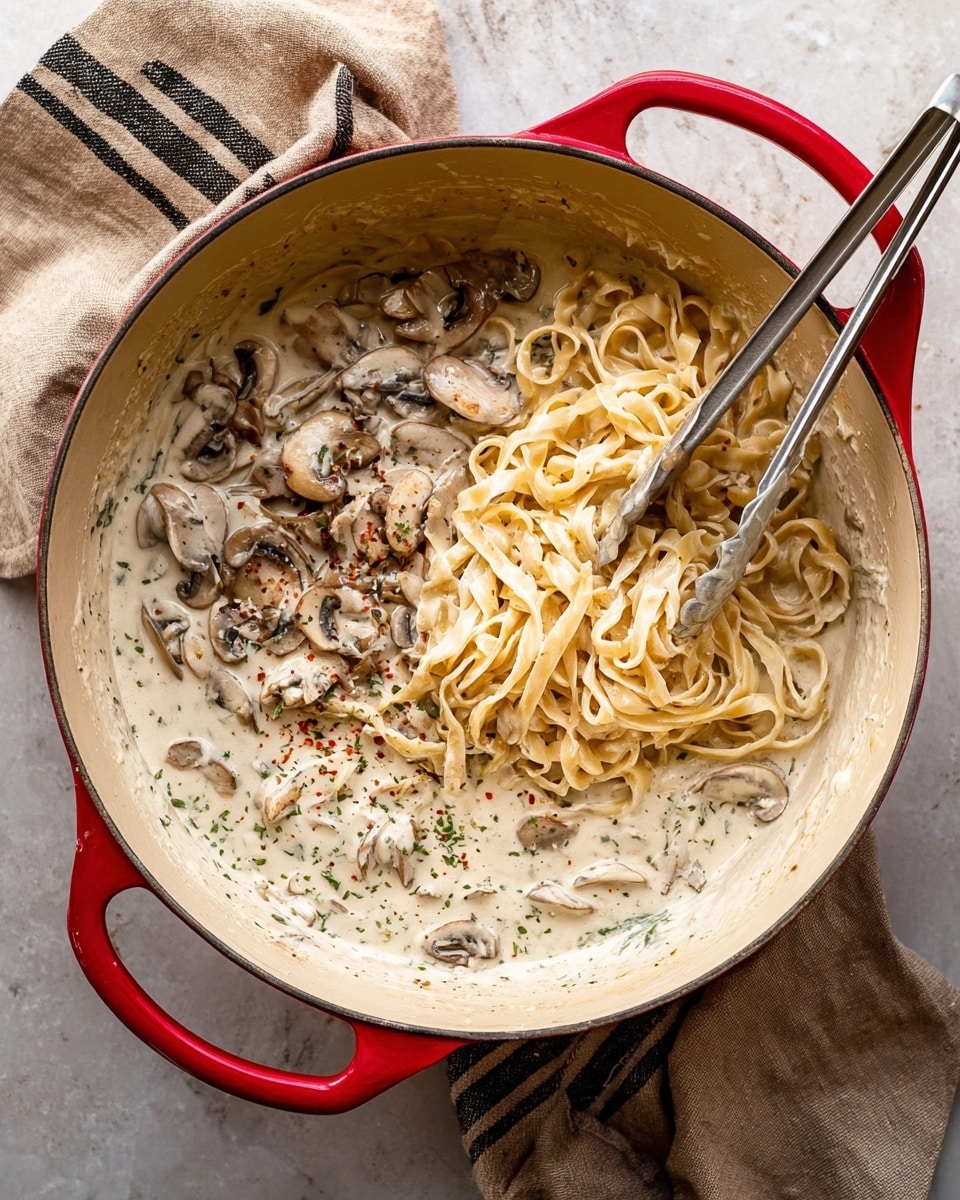 A creamy, light beige sauce with small green and black specks from herbs and seasoning fills a white pot, with slices of brown mushrooms scattered throughout. A wooden spoon rests inside the pot, partially covered with the sauce, showing some sauce texture on its surface. The background is a white marble textured surface. photo taken with an iphone --ar 4:5 --v 7
