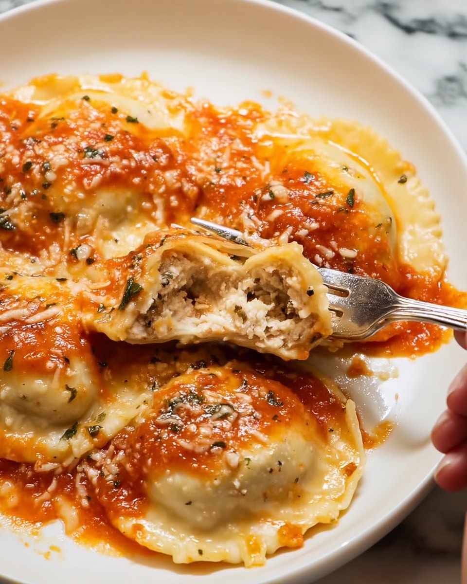 The image shows a close-up of a white plate holding multiple ravioli pieces filled with a creamy, light beige mixture. The ravioli are topped with a shiny, reddish-orange tomato sauce that has a slightly chunky texture and is sprinkled with small bits of grated cheese and herbs. One ravioli is cut open, revealing its soft and creamy filling inside. A silver fork is resting on the plate's edge, and a woman's hand is gently holding one ravioli piece. The plate is placed on a white marbled surface. photo taken with an iphone --ar 4:5 --v 7