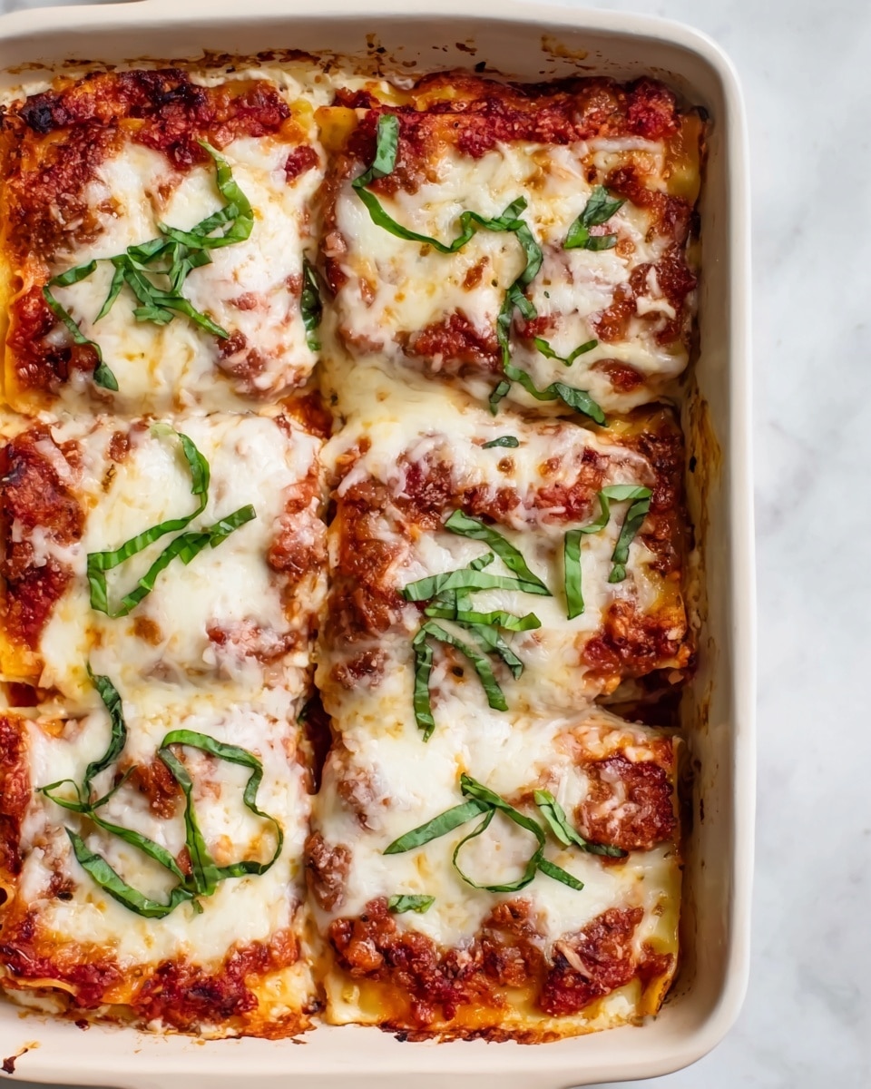 A white baking dish holds six square slices of lasagna arranged in two rows of three. Each slice shows thick layers, with a bright red tomato sauce base topped by a plentiful melted layer of soft white cheese, slightly browned in spots. Fresh thin strips of green basil are scattered on top, adding color contrast. The edges of the lasagna reveal a creamy layer beneath the sauce and cheese. The baking dish sits on a white marbled surface. Photo taken with an iphone --ar 4:5 --v 7
