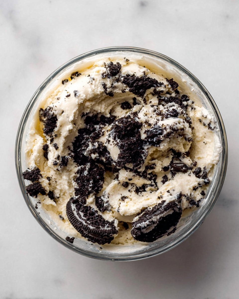 Fifteen round dough balls are arranged neatly in a 3 by 5 grid on a sheet of white parchment paper, placed on a white marbled surface. Each ball is light beige with dark brown and black crumbly speckles evenly mixed throughout, giving a textured, spotted look. The dough balls are smooth and uniformly shaped, with a slight sheen on their surface, indicating moisture. The overall scene is bright and clean, focusing on the contrasting colors of the dough and specks, with soft natural lighting creating gentle shadows around each ball. Photo taken with an iphone --ar 4:5 --v 7