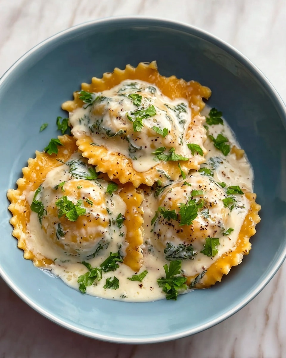 A bowl filled with about seven large, round ravioli pieces that have a soft orange color with ruffled edges. The ravioli are covered with a creamy white sauce that has small bits of dark green herbs or spinach mixed in. On top of the sauce, there are small pieces of fresh green herbs scattered for garnish. The bowl holding the ravioli is white and sits on a white marbled surface. photo taken with an iphone --ar 4:5 --v 7