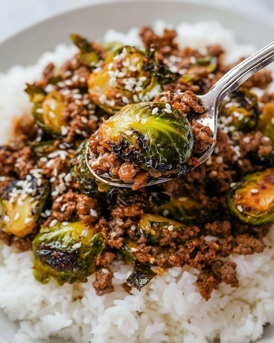 The dish shows a close-up of a spoonful of cooked ground meat mixed with cooked green and slightly charred Brussels sprouts, sprinkled with white sesame seeds. This mixture sits on a base layer of plain white rice that fills the background. The Brussels sprouts have a tender, slightly wilted texture with some leaves crispy and brownish. The ground meat is finely crumbled and coated in a glossy, dark sauce. The spoon is silver, holding a layered bite of the meat and Brussels sprout halves over white rice on a white marbled surface. Photo taken with an iphone --ar 4:5 --v 7