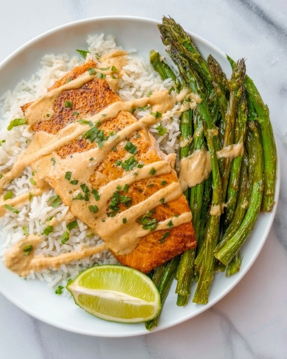 A white plate contains a meal with three main layers: the base layer is a bed of white rice with some green herb garnish sprinkled on top. In the middle sits a golden-brown cooked salmon fillet with a slightly crispy texture. Over the salmon, a light tan creamy sauce is drizzled in thin lines. To the side, there are green roasted asparagus spears with a slight char on some tips. A wedge of lime with light green inside is placed on the edge of the plate. The plate is set on a white marbled surface. Photo taken with an iphone --ar 4:5 --v 7