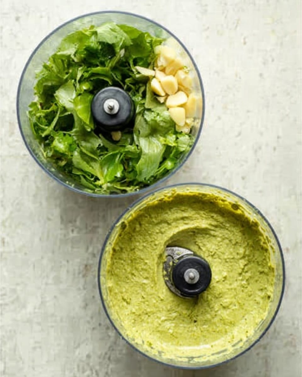 The image shows two clear round food processor bowls placed side by side on a white marbled surface. The bowl on the left contains fresh green leaves and small pieces of pale yellow garlic, ready for processing. The bowl on the right displays a smooth, pale green sauce with a slightly creamy texture, filling most of the bowl and the blade still visible in the center. Photo taken with an iphone --ar 4:5 --v 7