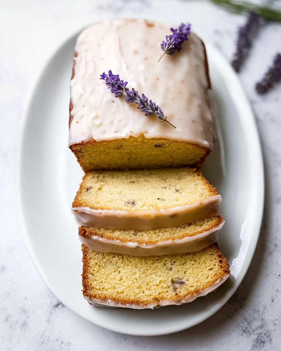 A white oval plate holds a loaf cake with three thick slices cut and placed in front, showing a soft, light yellow crumb with small dark specks throughout. The top of the loaf is covered in a smooth, shiny, off-white glaze, and two small sprigs of purple lavender rest on top for decoration. The plate sits on a white marbled surface. photo taken with an iphone --ar 4:5 --v 7
