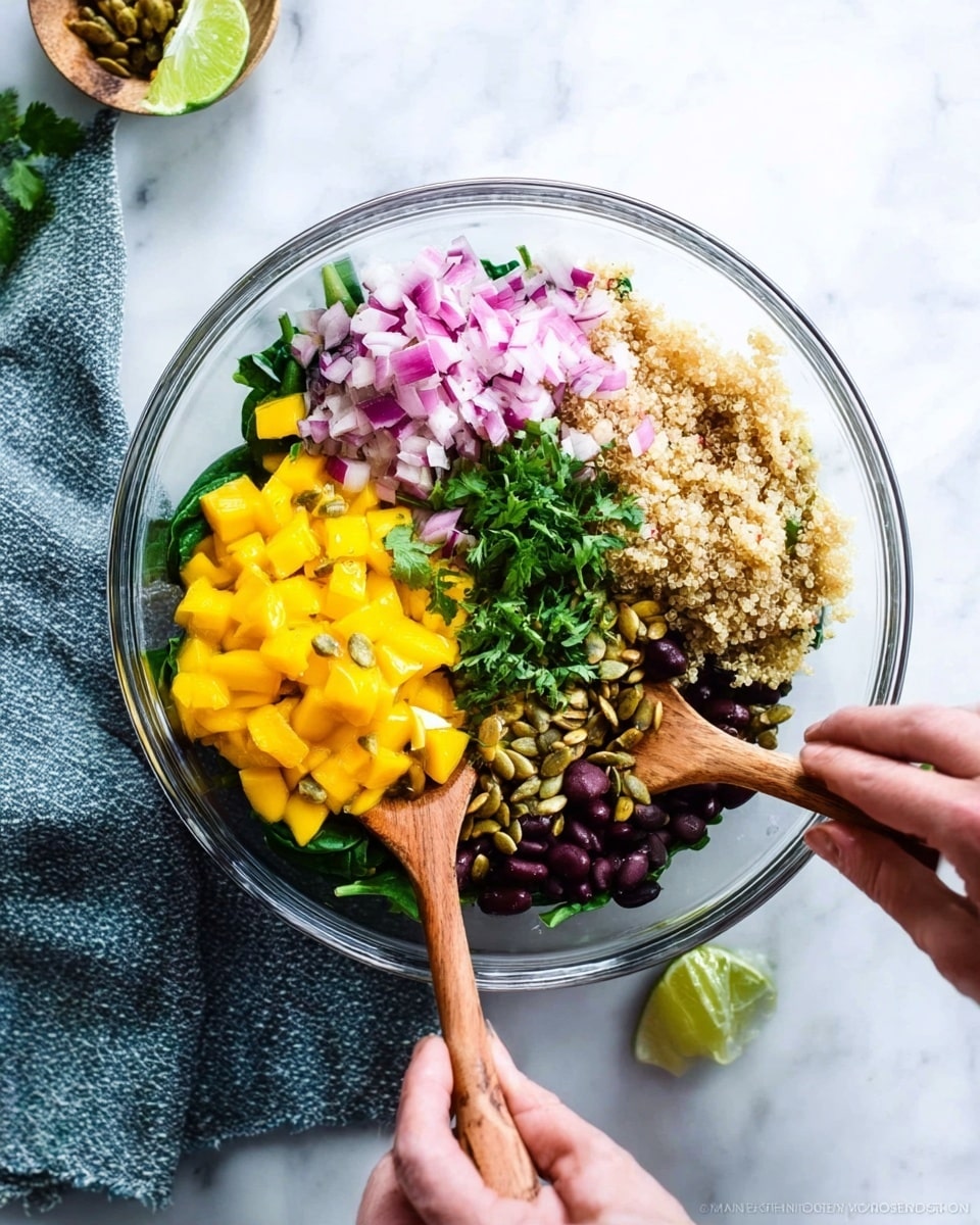 A clear glass bowl sits on a white marbled surface, filled with many colorful layers of fresh ingredients arranged side by side. The bottom layer is bright green leafy spinach spread beneath everything. On top of that, starting from one side, there is a vibrant yellow pile of diced mangoes, next to chopped red onions with their pink-purple shade, and beside them fluffy, light beige quinoa. Near the quinoa are dark black beans, and some roasted pumpkin seeds scattered on top. Small green chopped herbs, likely cilantro, are placed near the beans, adding more green color. Two wooden spoons stir the ingredients, held by two woman's hands from opposite sides of the bowl. The scene is bright and fresh, with a white marbled background and a blue-gray textured cloth partially visible under the bowl. Photo taken with an iphone --ar 4:5 --v 7
