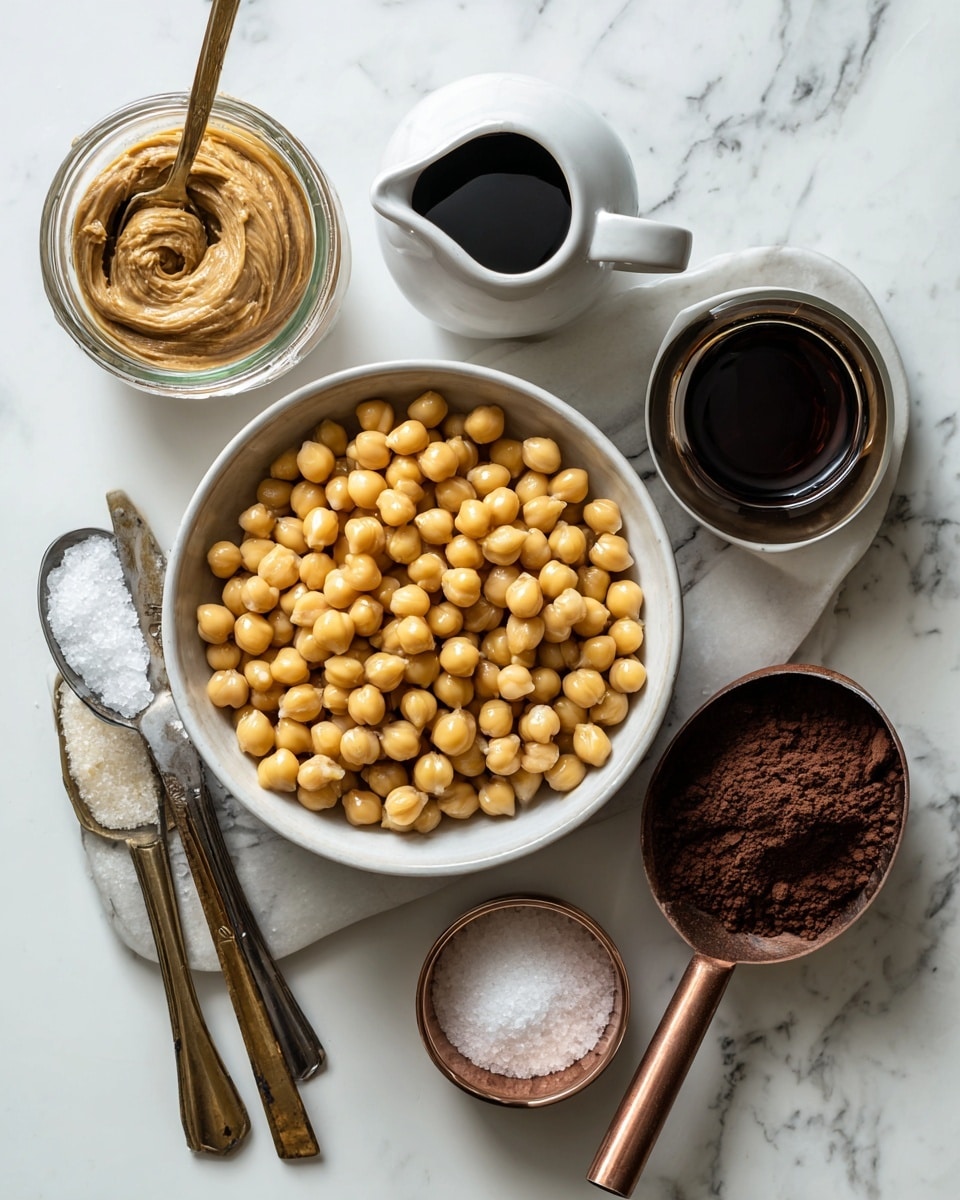 A white bowl filled with light yellow chickpeas sits on a dark baking sheet along with a small white pitcher of dark maple syrup, a small white bowl of light brown sugar, a glass container of creamy nut butter, a small clear container of dark vanilla extract, a copper scoop of rich dark cocoa powder, and a white spoon holding white salt. All containers and utensils are neat with visible textures of each ingredient against a white marbled surface. photo taken with an iphone --ar 4:5 --v 7