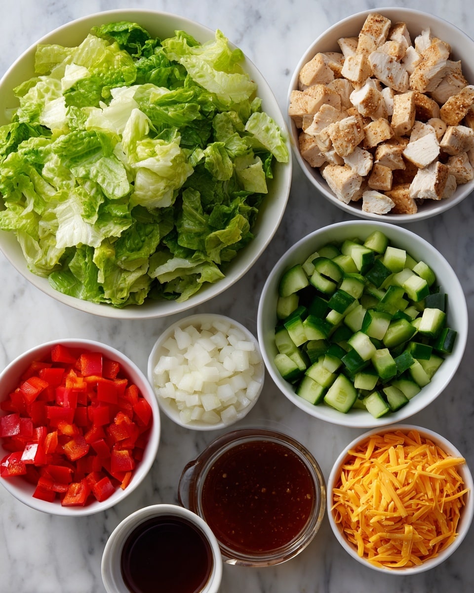 The image shows several white bowls and a small cup arranged on a white marbled surface, each containing a different salad ingredient. One large bowl is filled with chopped bright green romaine lettuce with a crisp texture. Another bowl holds diced red bell pepper and dark green cucumber pieces mixed side by side. A medium bowl contains cubed light tan cooked chicken pieces. There is a small bowl with finely chopped white onion, and another small bowl filled with shredded orange cheddar cheese. Next to the bowls is a small cup of creamy white ranch dressing and a small cup of dark reddish-brown hot honey sauce. The arrangement is neat and colorful, showcasing fresh and cooked ingredients side by side photo taken with an iphone --ar 4:5 --v 7