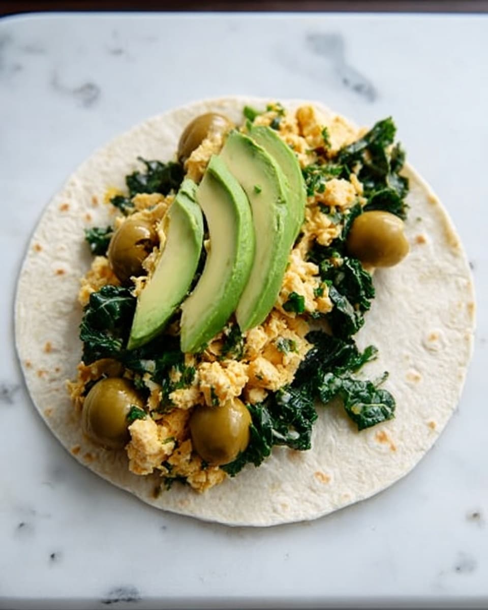 A soft white tortilla is laid flat on a white marbled surface, with a middle layer of cooked scrambled eggs mixed with green herbs for texture and color. On top of the eggs, there is a layer of dark green fresh spinach or kale leaves, adding a leafy texture, followed by a few green olives with their soft yellow-green color scattered along the spinach. At the top, slices of ripe avocado with smooth green flesh are placed slightly overlapping. The overall colors are light beige for the tortilla, yellow and green for the eggs and herbs, dark green for the leaves, pale green for the olives, and bright green for the avocado slices. photo taken with an iphone --ar 4:5 --v 7