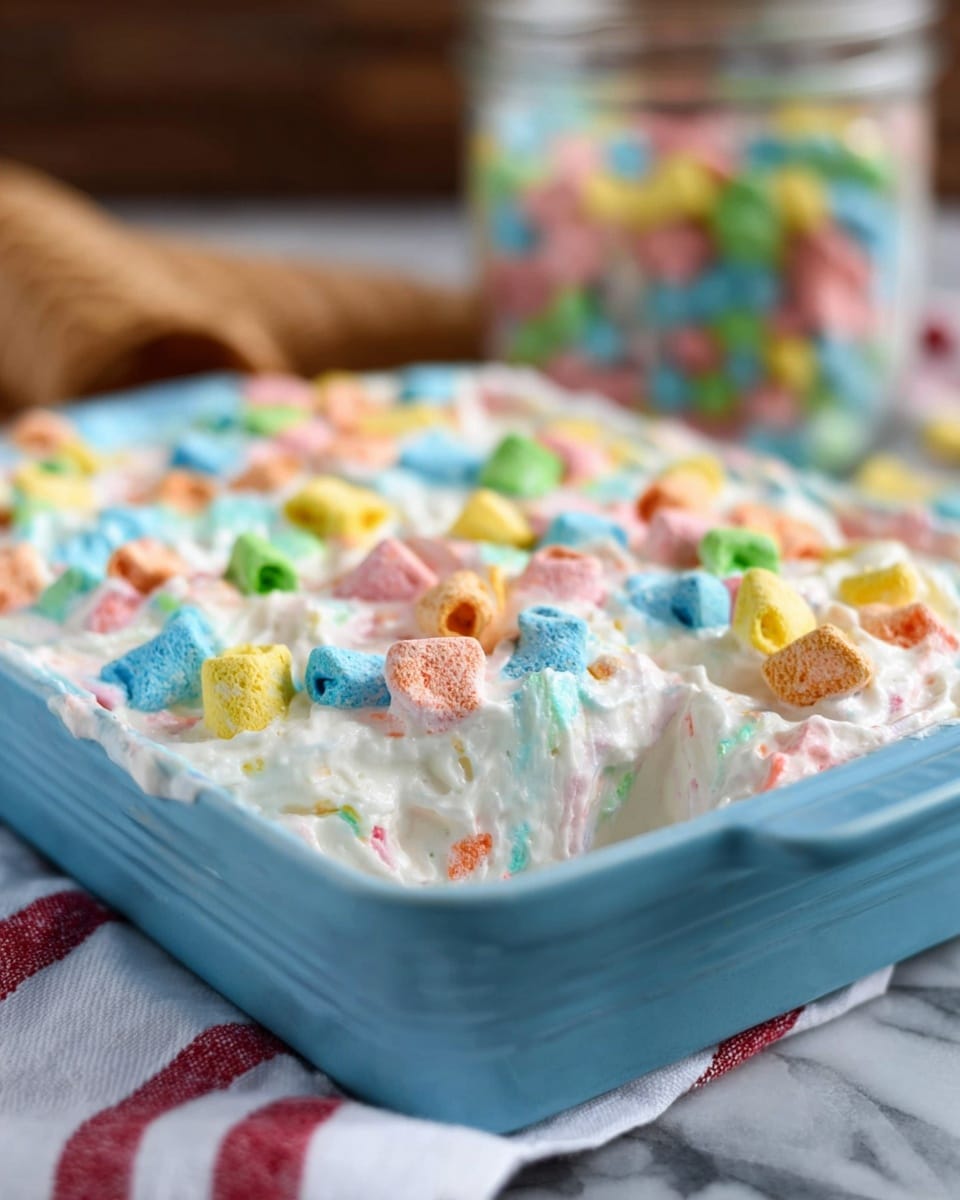 A close-up view of a blue speckled rectangular dish filled with creamy white ice cream mixed with colorful marshmallow pieces scattered throughout. The ice cream has a smooth and soft texture with small pastel pink, blue, yellow, green, and orange marshmallows embedded in it, creating a playful, multicolored look. A scoop of the ice cream with the same texture and colorful marshmallows is partially lifted in the center of the dish. In the background, a white marbled surface contrasts gently with the dish, and an empty waffle cone is placed on the side, partially visible. A white cloth with a red stripe is beneath the dish, adding a subtle cozy touch. photo taken with an iphone --ar 4:5 --v 7