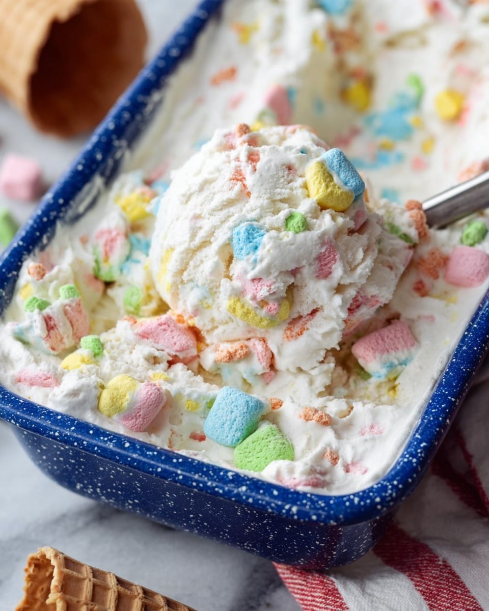 A close-up of a light blue rectangular baking dish filled with a thick, creamy white layer that has colorful, chunky marshmallow pieces scattered on top, adding splashes of bright colors like blue, green, yellow, orange, and pink. The dish rests on a white cloth with red stripes, against a blurred background that includes a glass jar filled with similar colorful marshmallows and a waffle cone piece. The surface beneath everything is a white marbled texture. photo taken with an iphone --ar 4:5 --v 7