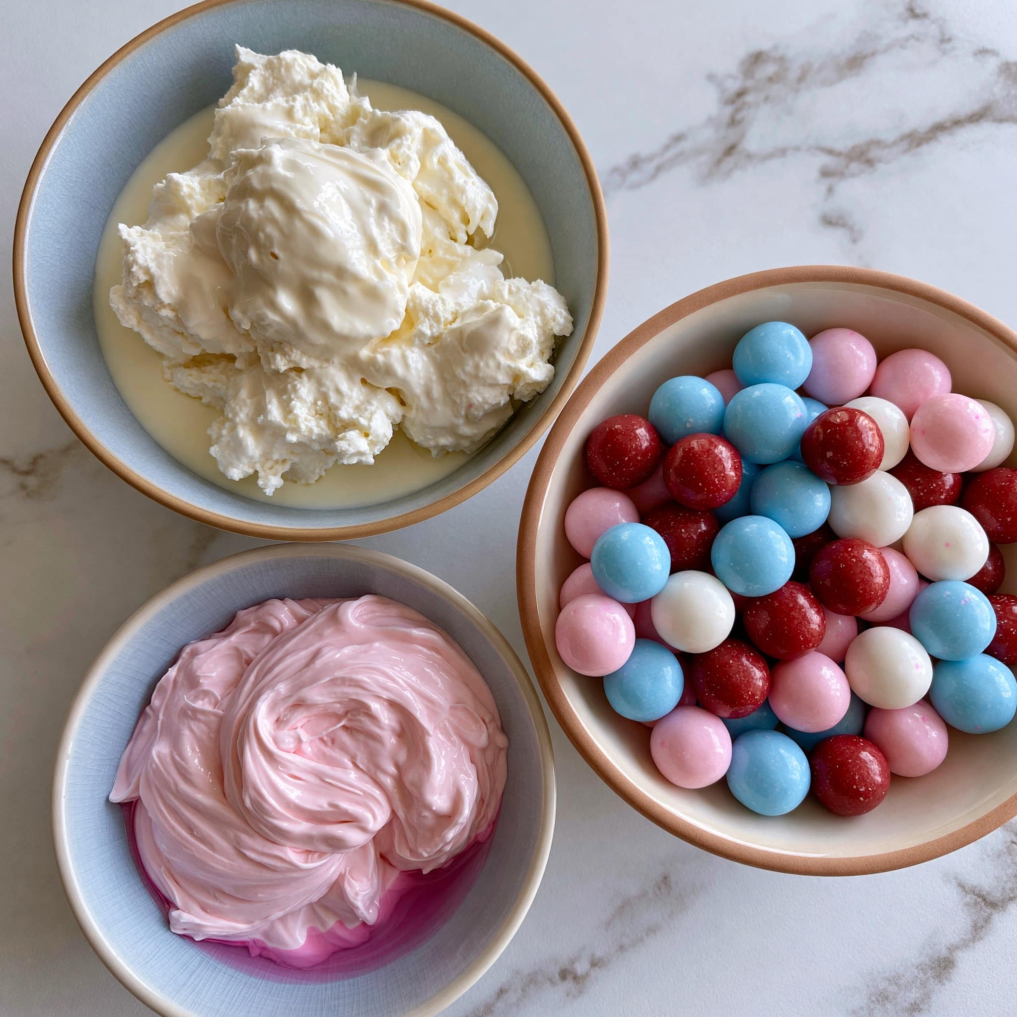 A tall white ice cream cup holds two large scoops of pink ice cream with small colorful pieces inside, giving it a textured look. In the background on the left, there is a white square bowl with more of the same pink ice cream. A black spoon lies on a white marbled surface to the right of the ice cream cup. The background is bright and softly blurred, creating a light and airy feel. photo taken with an iphone --ar 4:5 --v 7