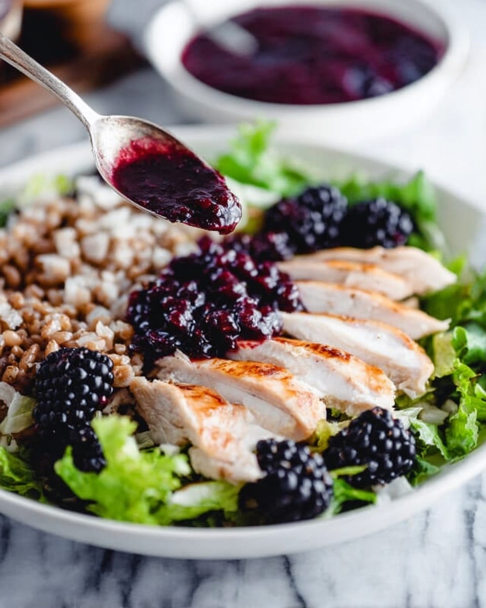 A white deep plate holds a fresh salad with multiple layers: the base layer has green leafy lettuce and some shredded purple cabbage on the side; on top there is a layer of thick light brown nuts slightly clustered, and spread over the salad are shiny blackberries. At the front and center, there are slices of juicy cooked chicken arranged in a fan shape, topped with a dark purple chunky sauce. The plate is on a white marbled surface, and a white bowl with more sauce is slightly blurred in the background. photo taken with an iphone --ar 4:5 --v 7