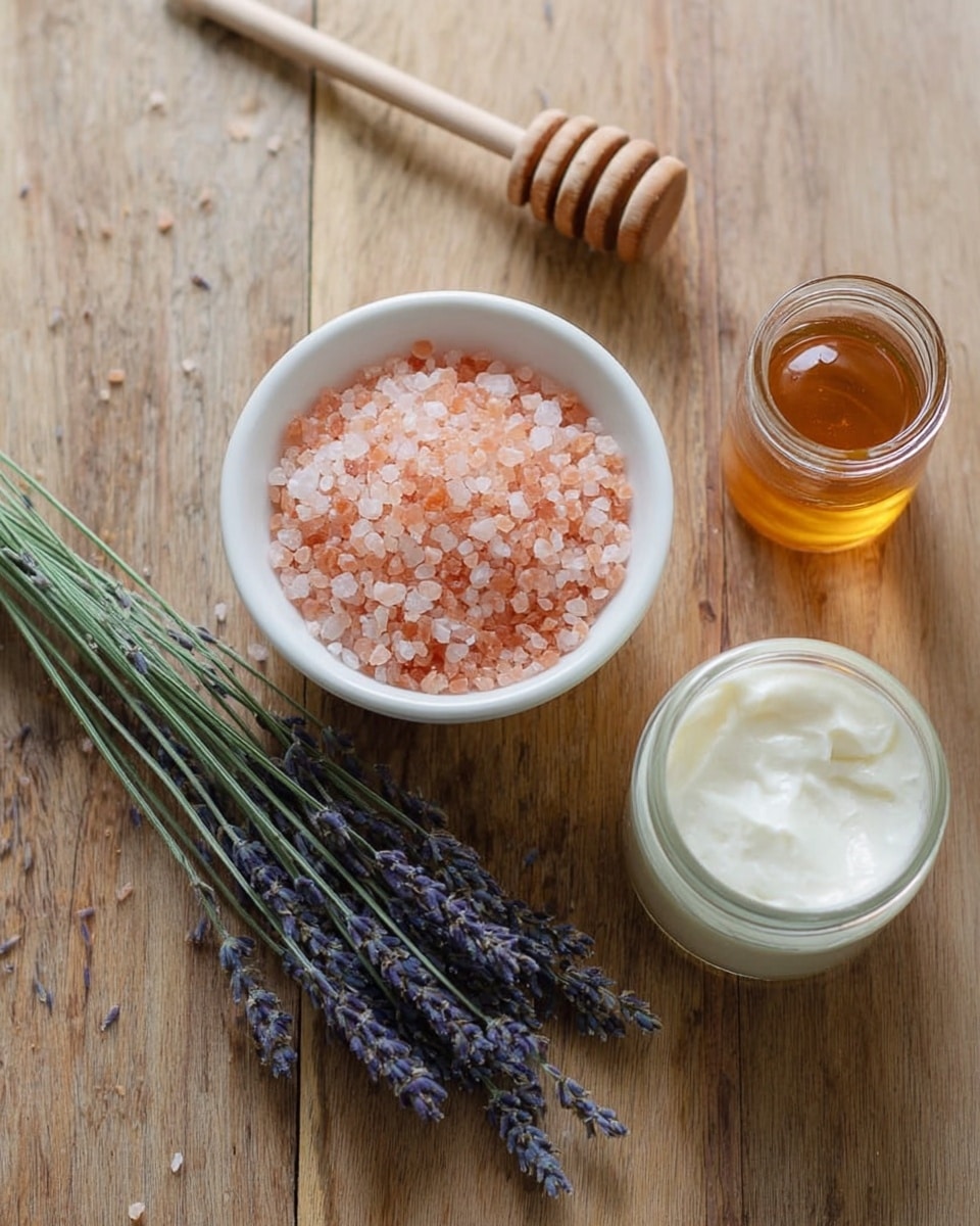 The image shows a small white bowl filled with pink salt crystals placed on a wooden surface. Next to the bowl is a small glass jar filled with a light brown liquid and a wooden honey dipper resting nearby. There is also a round glass jar with white creamy lotion inside. A thin bunch of dried lavender flowers with long stems lies diagonally across the surface, adding a natural touch. The background is a white marbled texture. Photo taken with an iphone --ar 4:5 --v 7