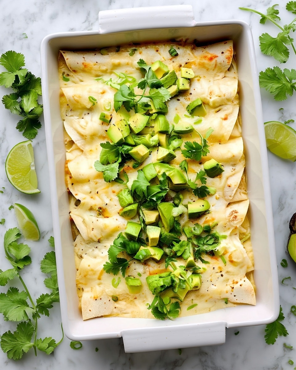 Two enchiladas covered with creamy white sauce lie on a white plate with a light blue rim. The enchiladas have a soft texture and are filled tightly, with the sauce slightly melted and dripping. On top, there are bright green avocado cubes, finely chopped green onions, and fresh cilantro leaves that add color and freshness. The plate sits on a white marbled surface with a blurred bowl of lime wedges and some greenery in the background. A black fork with a white handle rests beside the plate photo taken with an iphone --ar 4:5 --v 7